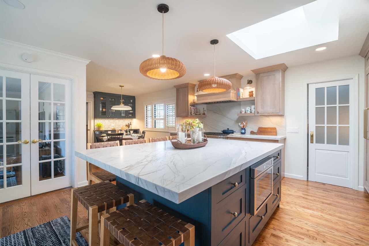 Kitchen remodeling contractor project featuring white shaker cabinets with contrasting dark island, classic subway tile backsplash, and pendant lighting accents.