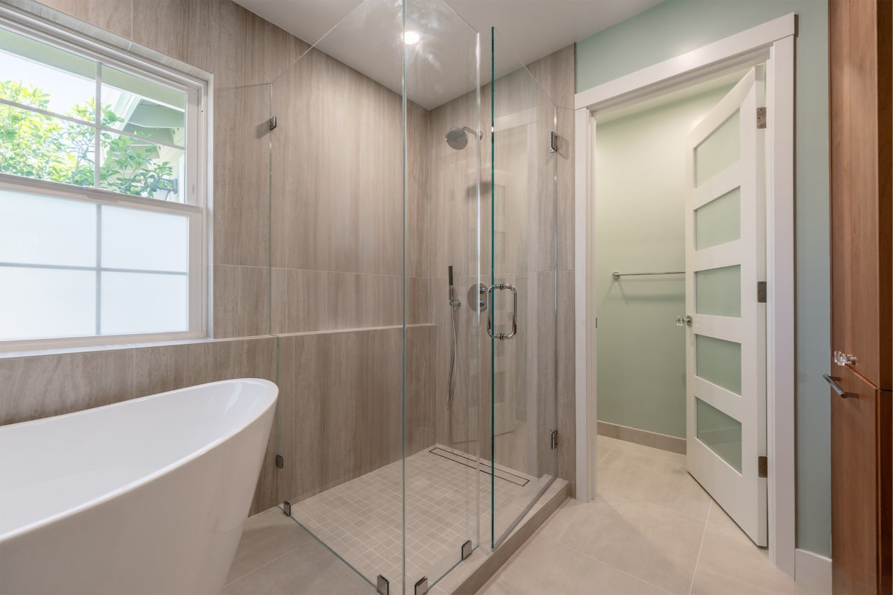 Thoughtfully designed guest bathroom with strategic lighting layouts highlighting custom wood vanity and frameless glass shower enclosure