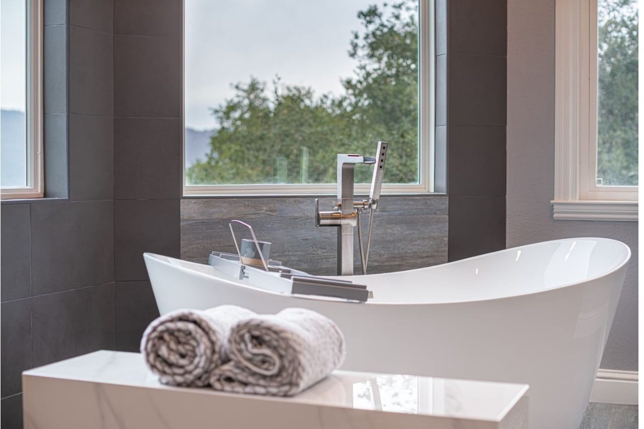 Stunning open concept bathroom design creating seamless indoor-outdoor living with modern black vanity and freestanding tub with garden views